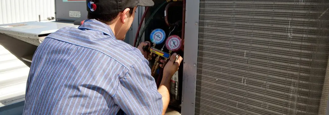 HVAC technician servicing a condenser unit in Bayou Blue
